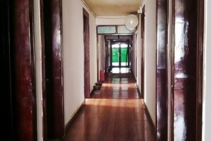 A long, narrow hallway with wooden floors and doors on both sides.