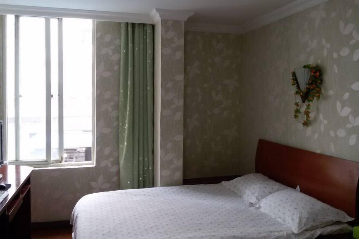 Una habitació d'hotel amb un llit, un escriptori i una finestra amb cortines.