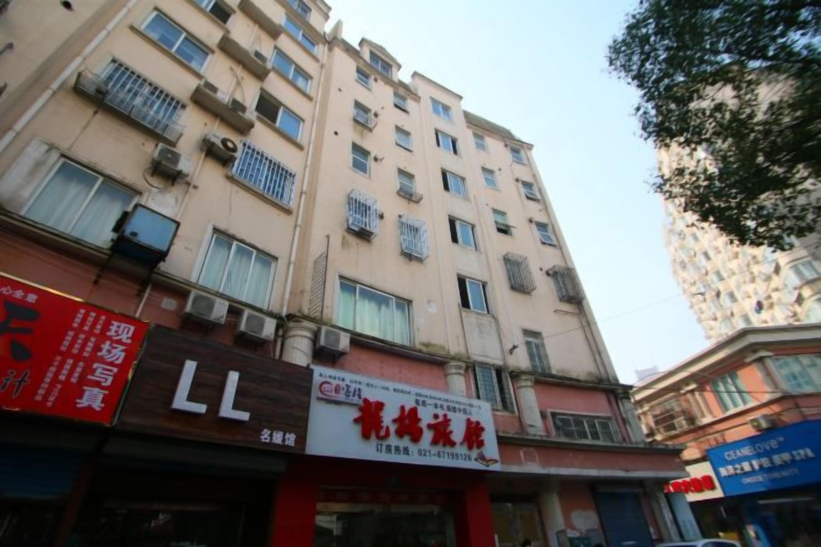 A multi-story building with commercial establishments on the ground floor, including a visible signboard and air conditioning units.