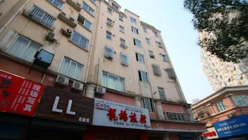 A multi-story building with commercial establishments on the ground floor, including a visible signboard and air conditioning units.