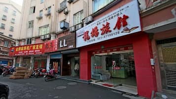A street view with several storefronts, including a red building with a glass front and a sign with Chinese characters.