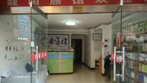 A hotel reception area with a reception desk, a sofa, and a bookshelf filled with books. - Longyang Inn (Shanghai)