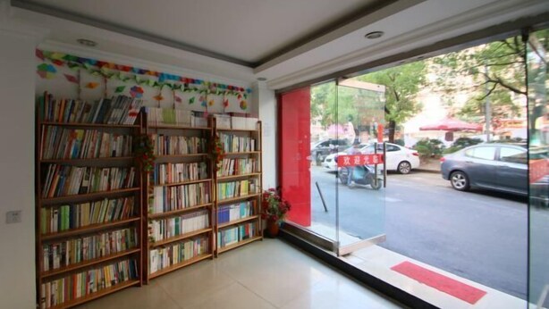 A library with bookshelves and a view of the street outside. - Longyang Inn (Shanghai)