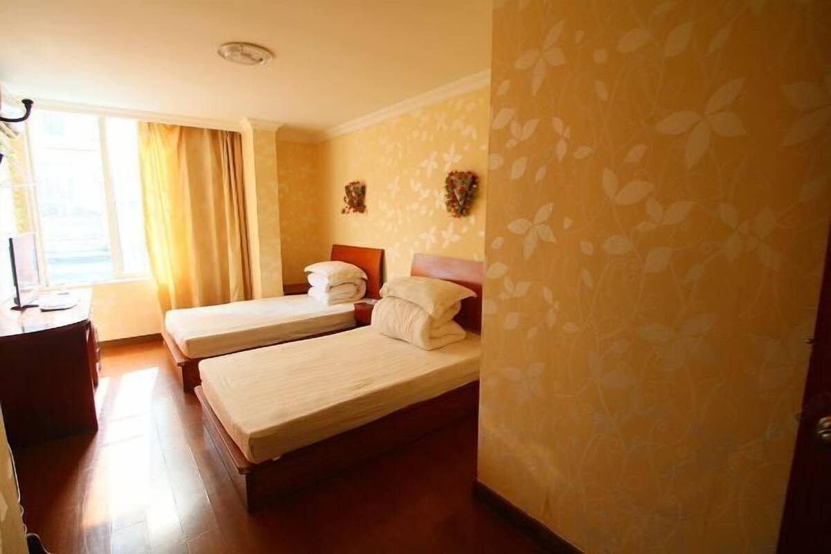 Habitació d'hotel amb dos llits, una taula de treball i una finestra amb cortines.