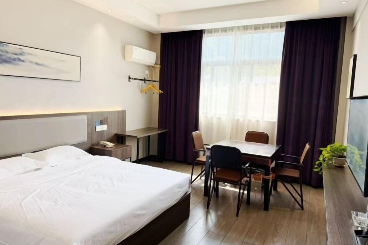 Una camera d'albergo con un letto, una scrivania, una sedia, un tavolo e una finestra con tende.