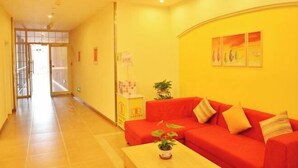 A hotel lobby with a red sofa, a small table with a plant, and a corridor leading to another room. - Home Inn (Beijing apple garden subway station store) (Beijing)