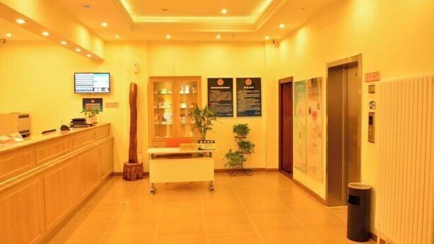 A hotel reception area with a reception desk, a computer monitor, a plant, and an elevator. - Home Inn (Beijing apple garden subway station store) (Beijing)