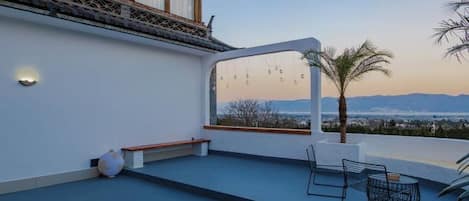 Una terraza en la azotea con vistas al paisaje, un espacio de estar y una mesa.
