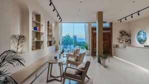 A modern living room with a sofa set, a coffee table, and a bookshelf. There is a large window providing a view of the outdoors. - When we first meet (Dali City)