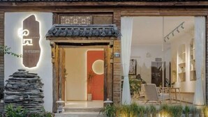 A traditional-style building with a wooden facade, a stone pillar, and a modern interior with a seating area. - When we first meet (Dali City)