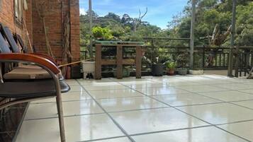Un espace extérieur pavé, avec un banc, des plantes en pot et une structure en forme de pergola.