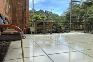 Un patio con baldosas, un banco, plantas en macetas y una estructura de pérgola.