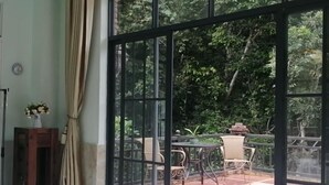 Une pièce dotée d’une grande porte-fenêtre coulissante qui donne sur un patio extérieur aménagé avec une table et des chaises.