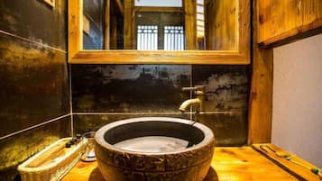 Un baño rústico con un lavabo grande de piedra, paredes de madera y un espejo sobre el lavabo.