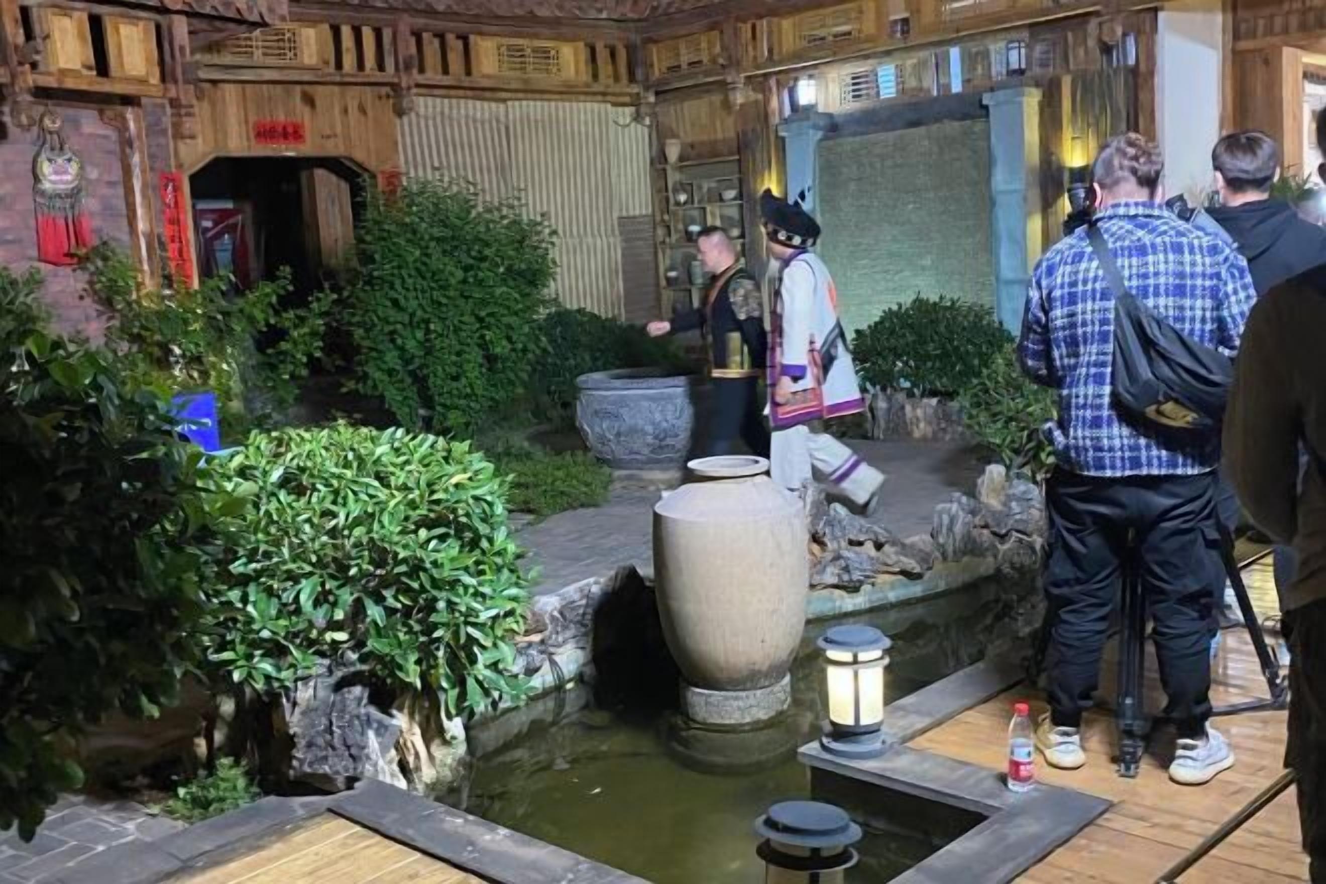 A traditional Japanese garden with a stone lantern, a koi pond, and a wooden walkway.