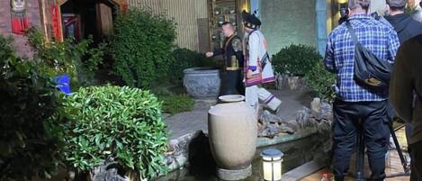 A traditional Japanese garden with a stone lantern, a koi pond, and a wooden walkway.