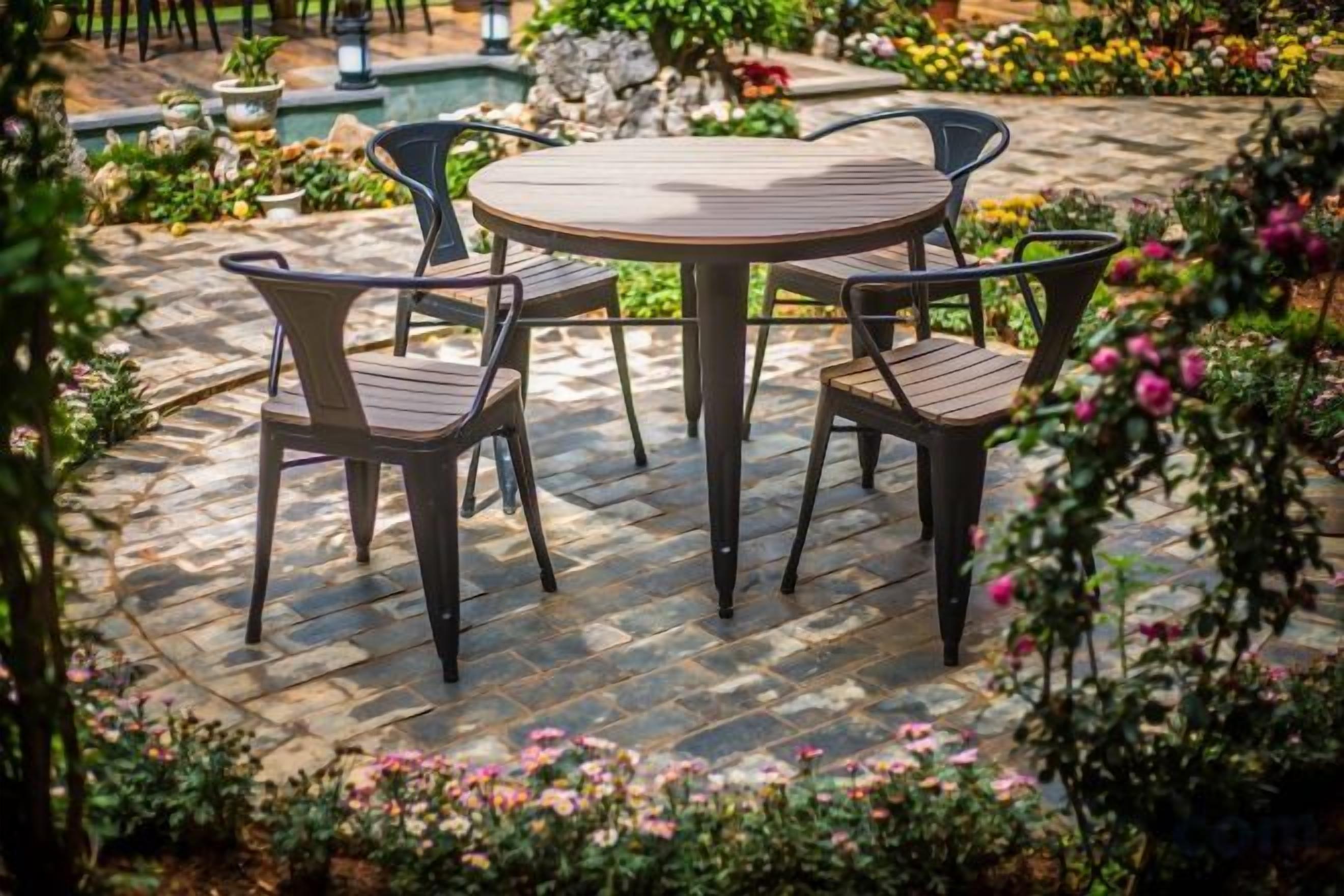Una mesa redonda con cuatro sillas en un jardín.