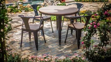 Una mesa redonda con cuatro sillas en un jardín.
