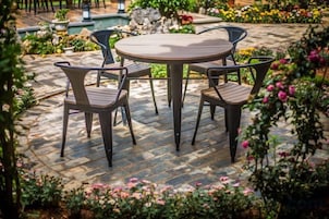 Una mesa redonda con cuatro sillas en un jardín.