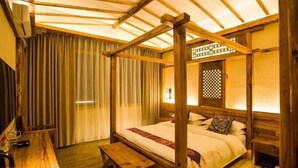 A traditional Japanese-style room with a four-post bed, wooden flooring, a desk with a chair, and a sliding door. - Sansheng Garden Inn (Puzhehei Xianrendong Shop) (Qiubei)
