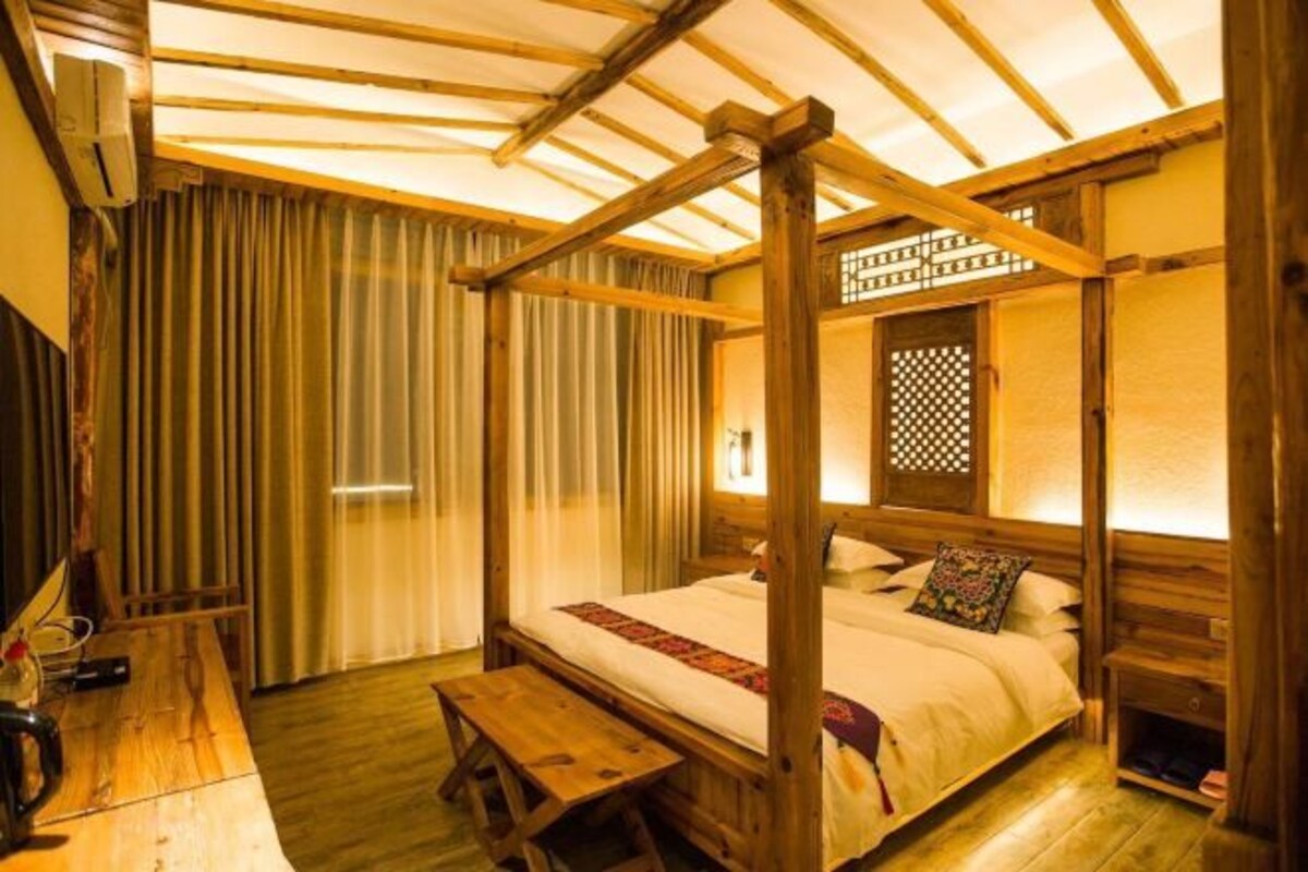 A traditional Japanese-style room with a four-post bed, wooden flooring, a desk with a chair, and a sliding door.
