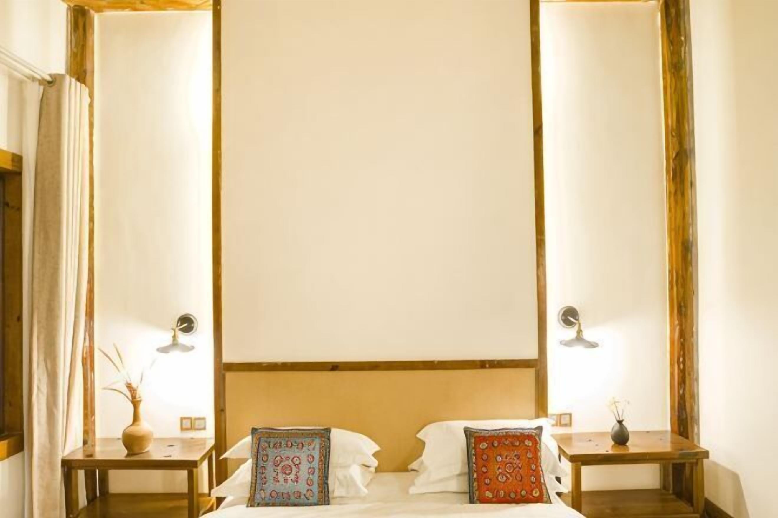 A room with a bed, two bedside tables, and a mirror.