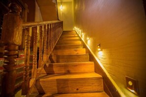 A wooden staircase with a handrail and wall-mounted lights. - Sansheng Garden Inn (Puzhehei Xianrendong Shop) (Qiubei)