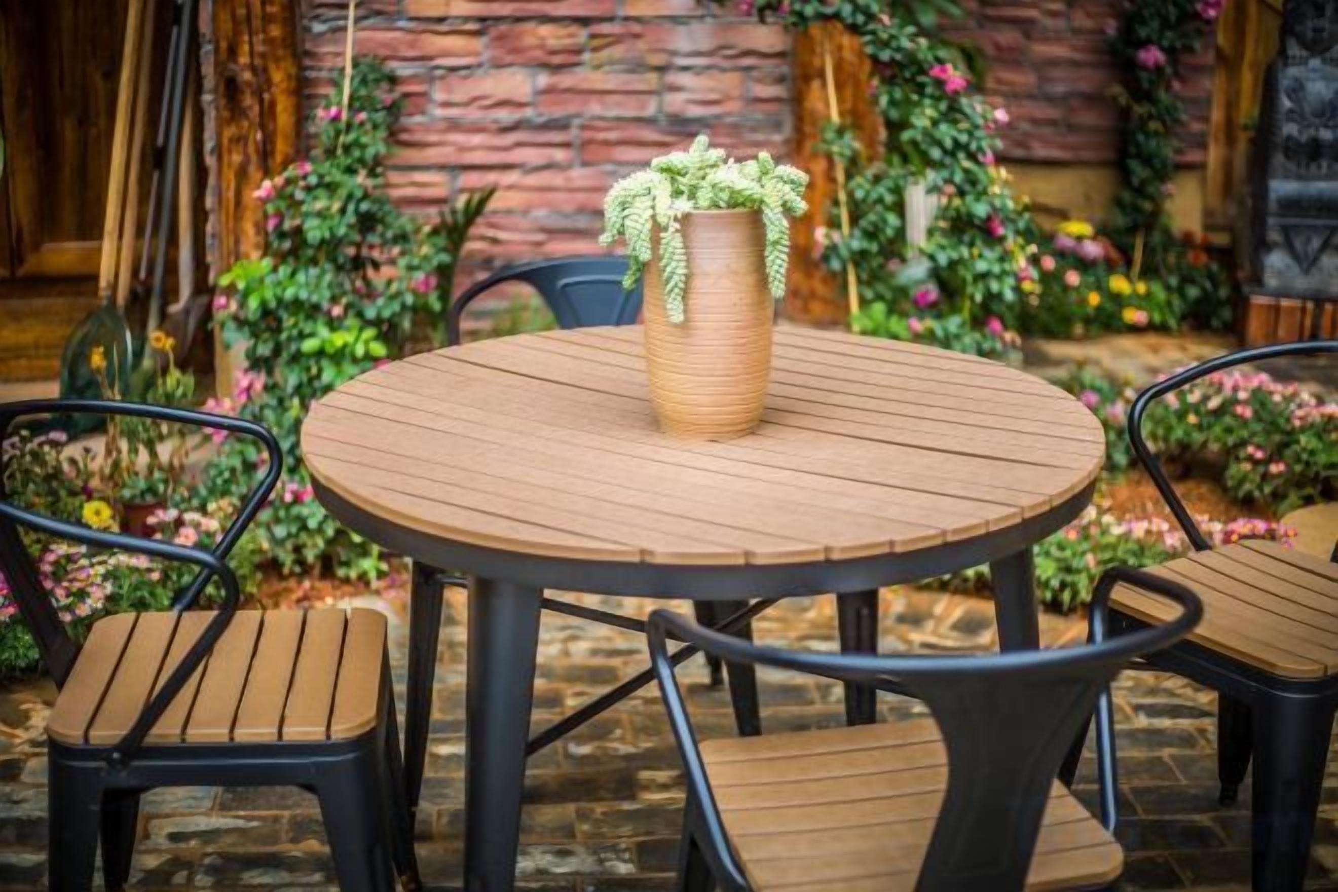Una mesa redonda de madera con un florero tejido y dos sillas.