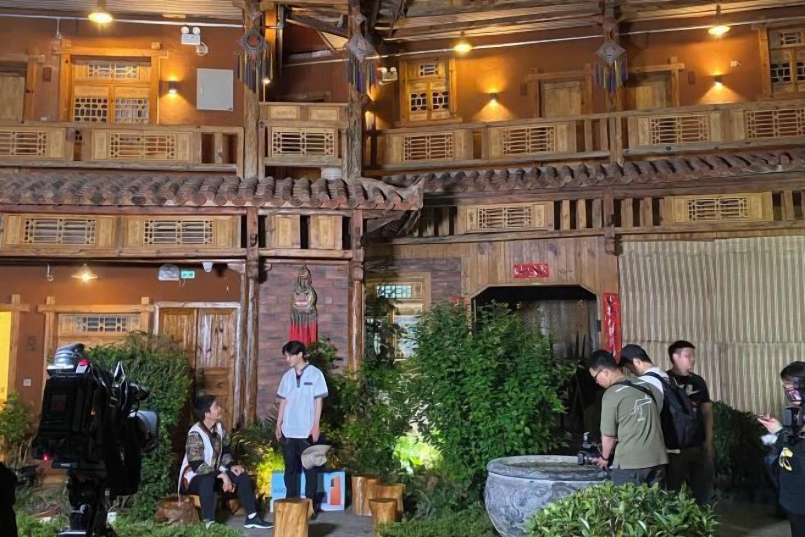 Un edificio de madera tradicional con varios niveles y balcones, rodeado de vegetación.
