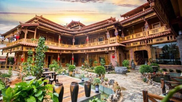 A traditional building with multiple balconies and a courtyard with potted plants and seating areas. - Sansheng Garden Inn (Puzhehei Xianrendong Shop) (Qiubei)