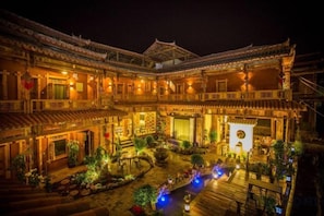 A traditional courtyard with a wooden deck, potted plants, and a fountain. - Sansheng Garden Inn (Puzhehei Xianrendong Shop) (Qiubei)