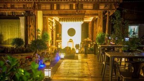 A traditional wooden building with a central open space, surrounded by tables and chairs, and illuminated by lanterns. - Sansheng Garden Inn (Puzhehei Xianrendong Shop) (Qiubei)