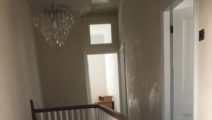 Eine Treppe mit hölzernem Geländer und weißen Spindeln, die zu einem Zwischenpodest mit einem kleinen Holztisch und einer weißen Tür führt.