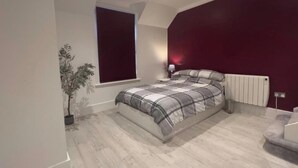Ein modernes Schlafzimmer mit einem großen Bett, einem Fenster, einer Heizung und einer Topfpflanze.