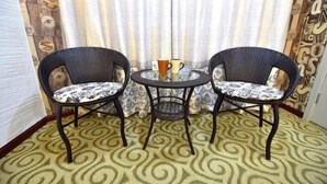 A room with two wicker chairs and a small round table, a patterned carpet, and curtains with a geometric design. - Hanxiangju Homestay (Wuzhen Xizha Scenic Spot) (Tongxiang)