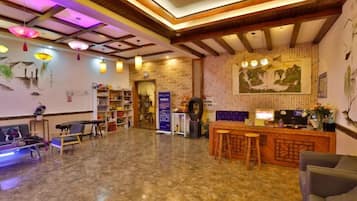 A hotel lobby with a reception desk, seating area, and a large wall mural.