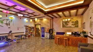 A spacious lobby with a polished marble floor, wooden ceiling beams, and a reception desk with a computer and a small seating area. - Hanxiangju Homestay (Wuzhen Xizha Scenic Spot) (Tongxiang)