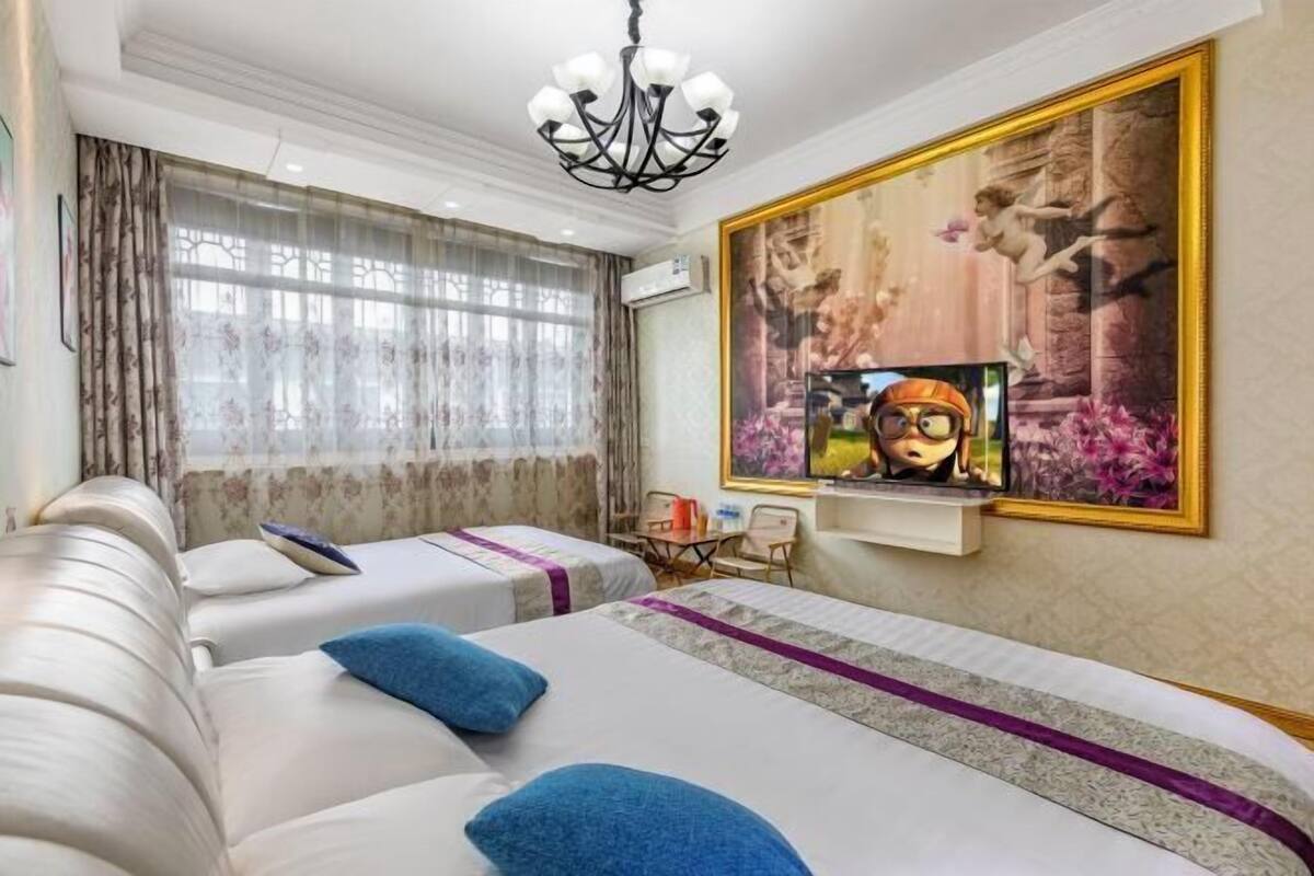 Ένα δωμάτιο ξενοδοχείου με δύο κρεβάτια, έναν καναπέ, ένα πολυέλαιο, έναν πίνακα και μια τηλεόραση.