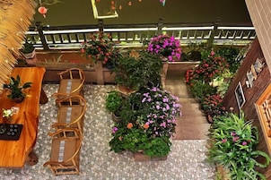 A rooftop terrace with seating, potted plants, and a railing.