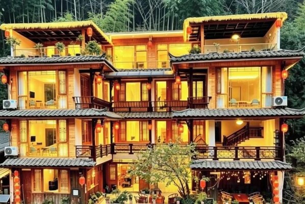A traditional multi-story building with balconies, large windows, and a thatched roof.