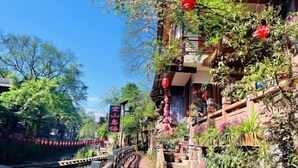 A traditional Chinese courtyard with a narrow waterway, wooden bridges, and red lanterns. - kong shan niao yumin su (Ya'an)