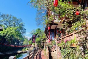 Een traditionele Chinese binnenplaats met een smalle waterweg, houten bruggen en rode lantaarns.