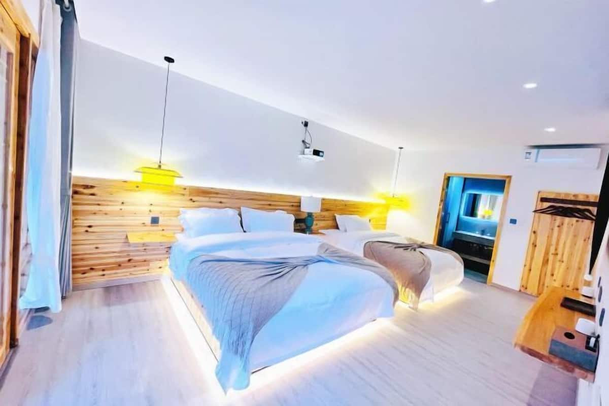 Een moderne hotelkamer met een houten hoofdeinde, twee bedden, een bureau en een douche.