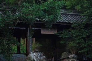 Een traditioneel Japans gebouw met pannendak, omringd door weelderige begroeiing.