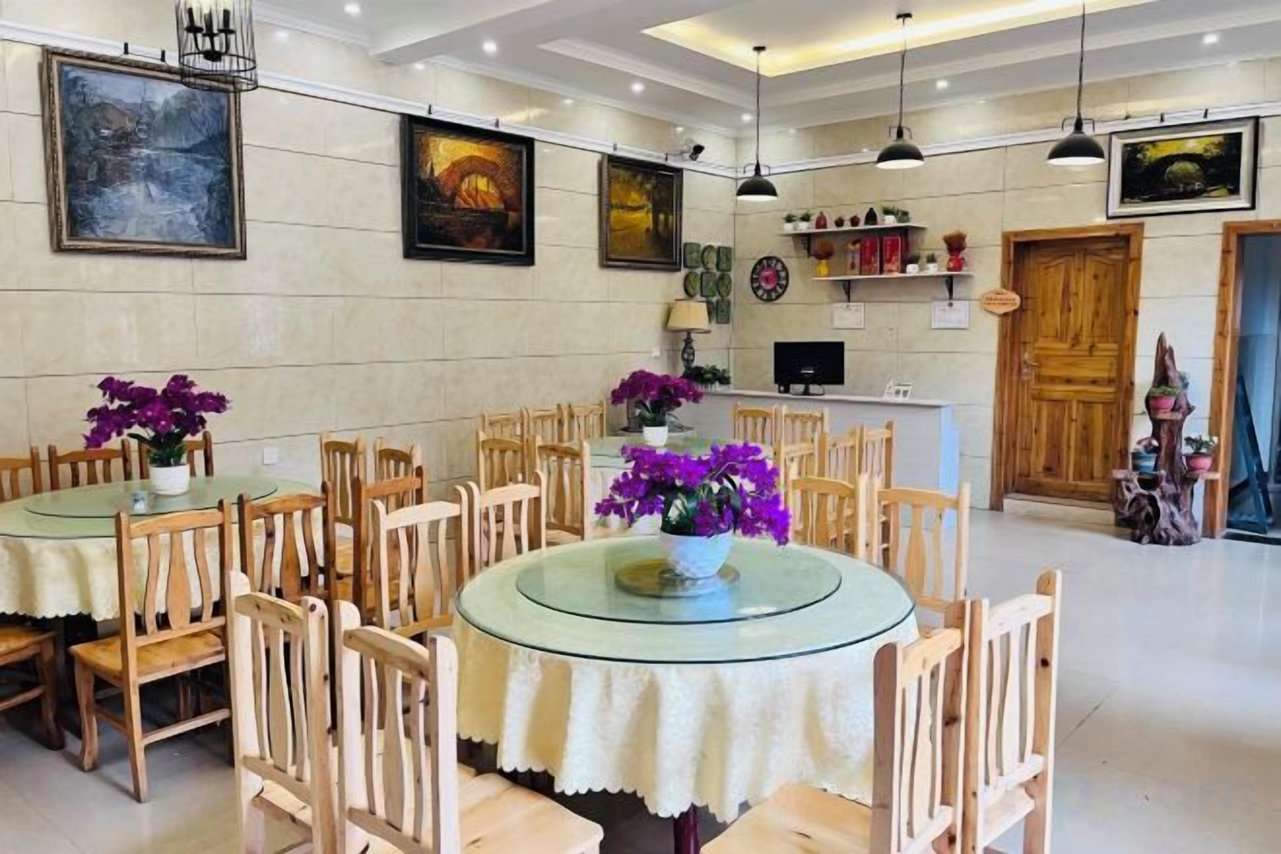 A dining area with round tables and chairs, a wooden door, and wall-mounted artwork.