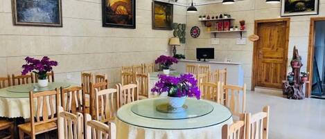 A dining area with round tables and chairs, a wooden door, and wall-mounted artwork.