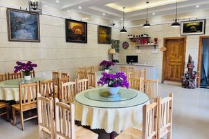 A dining area with round tables and chairs, a wooden door, and wall-mounted artwork.