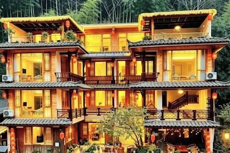 A traditional multi-story building with balconies, large windows, and outdoor seating areas.. kong shan niao yumin su