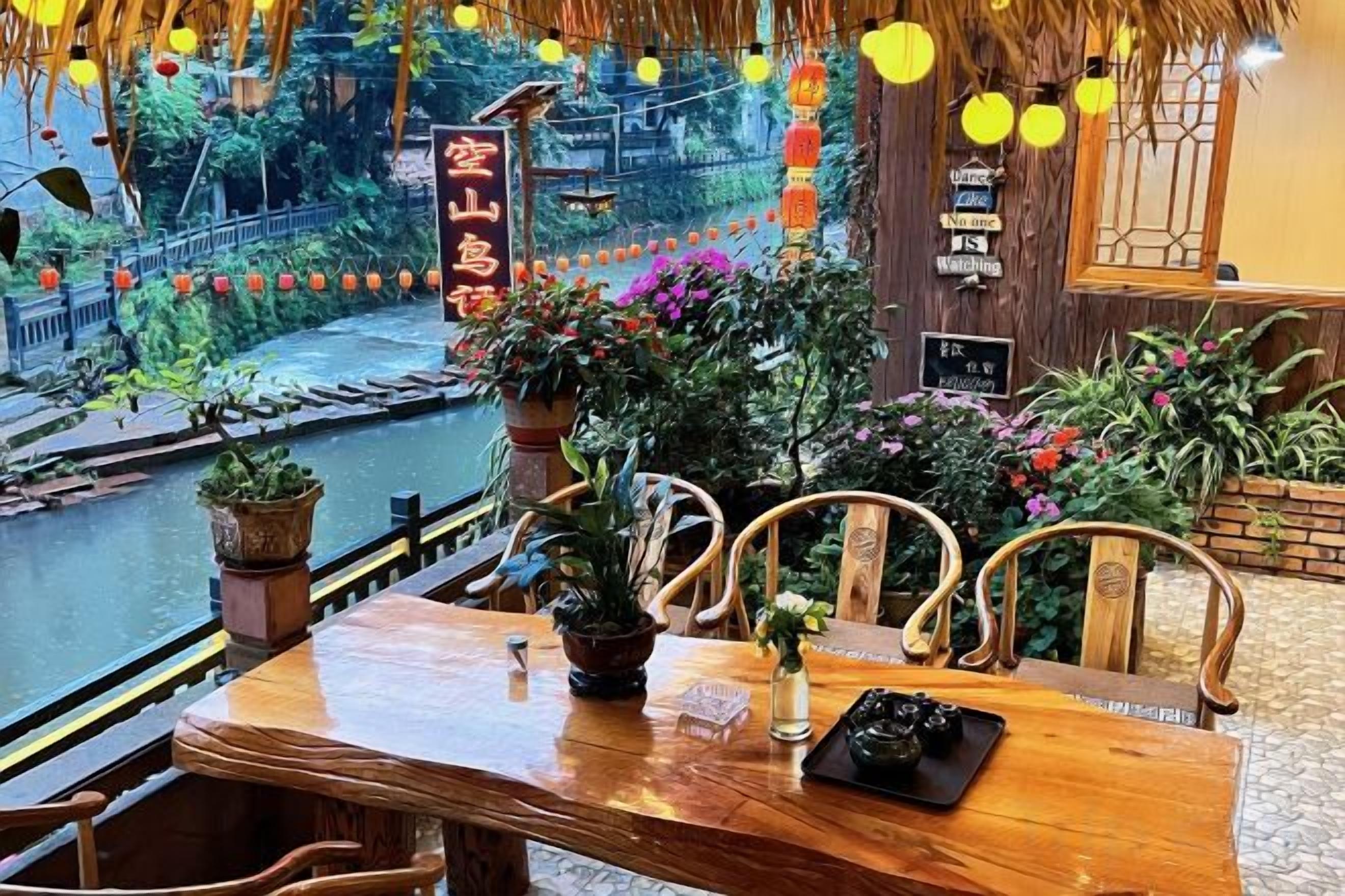 Mesa de madeira com cadeiras, plantas em vasos e vista para um rio.