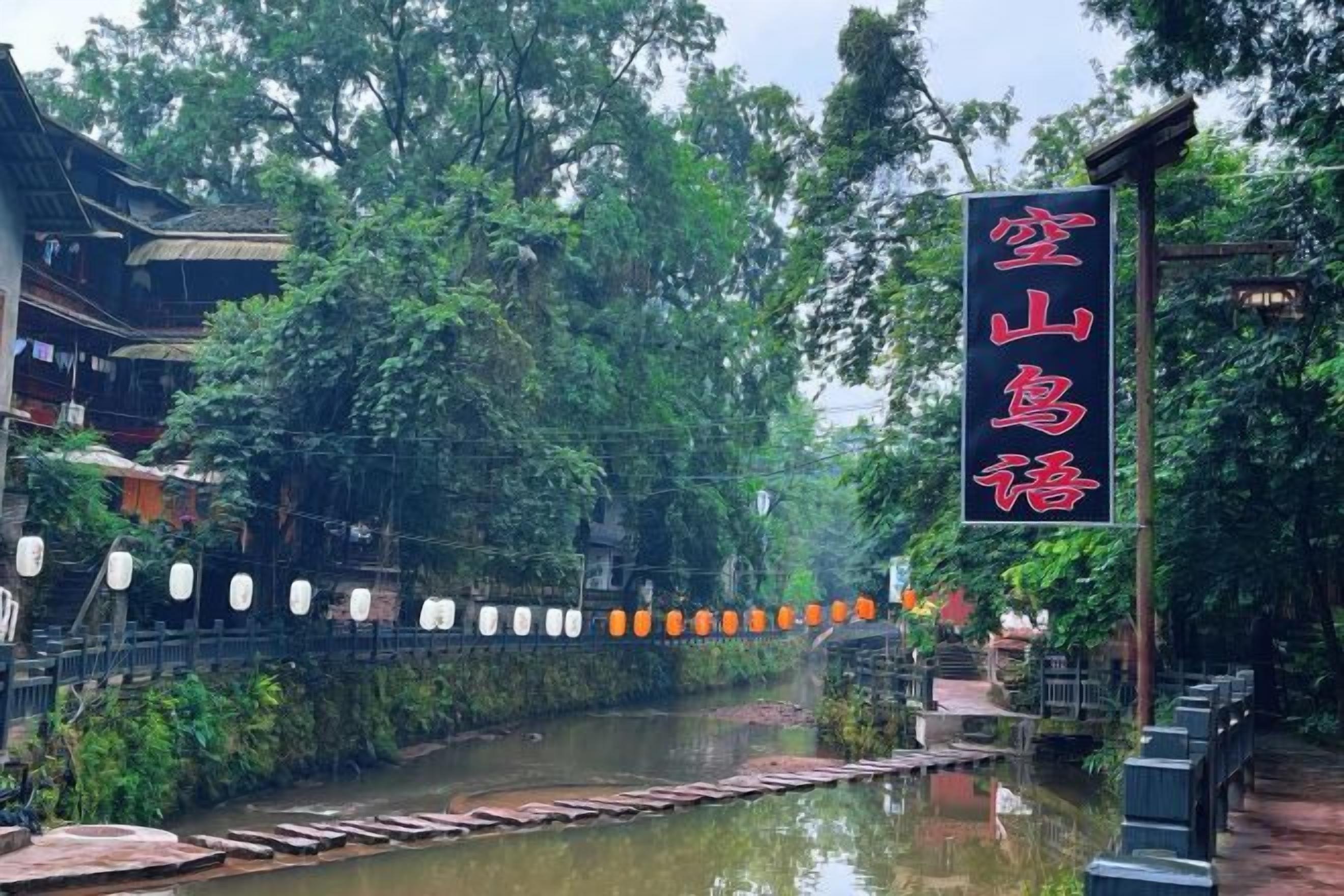 A traditional building with a sign in a foreign language, a river in front, and a bridge.